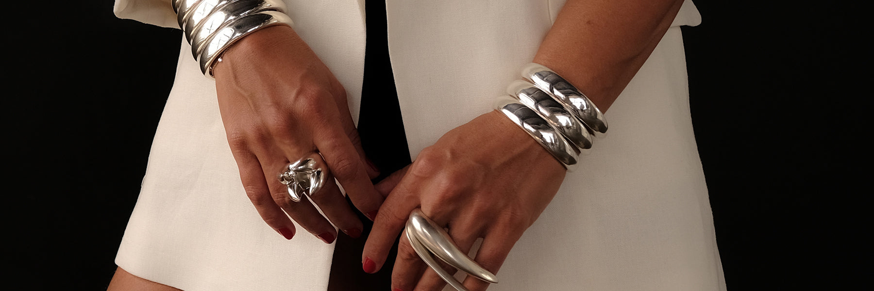 sterling silver sculptural cuffs and bracelets stacked on wrists - Jovana Djuric New York